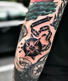 a man's arm with tattoos on it, including compass and other things in the background