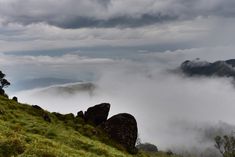 the clouds are rolling in and over the mountain tops, with rocks on each side