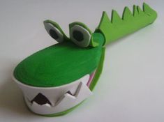 a close up of a toy alligator head on a white surface with one eye open