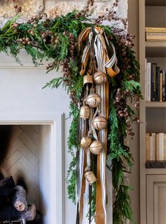 a christmas wreath with bells hanging from it's side next to a fire place