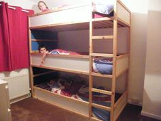 two children are sitting on top of bunk beds in a room with red drapes