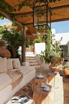 an outdoor living area with white couches and potted plants