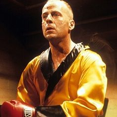 a man in a yellow jacket and red boxing gloves is looking off into the distance