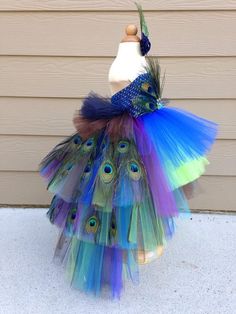 there is a multicolored tutu skirt on the back of a doll in front of a house