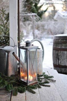 a lantern sitting on top of a wooden table next to a potted plant in front of a window