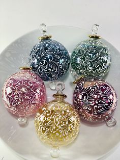 four different colored glass ornaments on a white plate