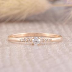 a gold ring with three stones on it and a feather in the background, sitting on top of a table