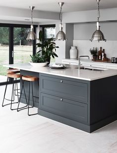 a large kitchen with an island and bar stools next to the window that looks out onto the yard