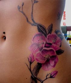 a woman's stomach with flowers painted on the side and behind her is a tree branch