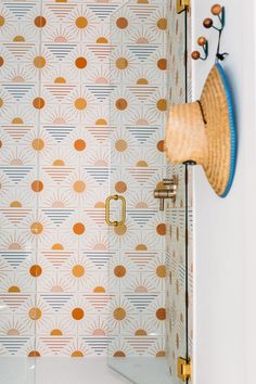 a bathroom with an orange and white wallpaper, gold accents and a wooden hat on the door handle