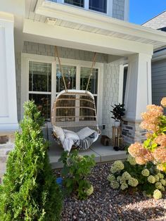 a bird cage sitting on top of a porch next to a flower bed in front of a house