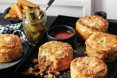 several pastries on a tray with dipping sauce and pickle sticks in the background