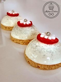 three desserts with white frosting and red decorations on them sitting on a plate