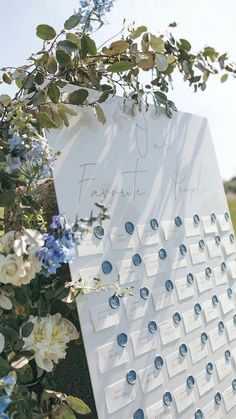 a white calendar with blue and white flowers on the front is surrounded by greenery