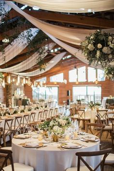 the tables are set up with white linens and greenery for an elegant wedding reception