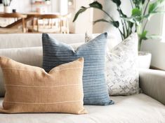 three pillows sitting on top of a white couch