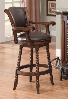 a wooden bar stool with brown leather upholstered back and arm rests on a hard wood floor