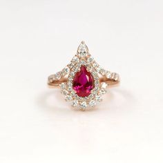 a close up of a ring with a red stone in the middle and white diamonds around it