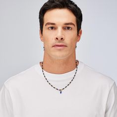 a man in a white shirt is wearing a necklace with blue beads on his neck