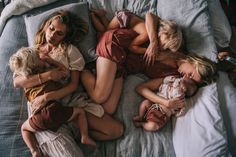 three women and two children are sleeping on a bed with their arms around each other