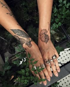 two people with tattoos on their hands holding each other's hands and one has a leaf tattoo on it