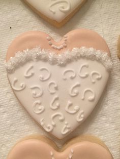 three decorated heart shaped cookies sitting on top of a table next to each other with white frosting