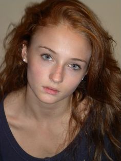 a girl with red hair is looking at the camera