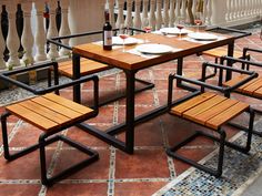 an outdoor dining area with wooden benches and tables on the side walk, along with wrought iron railings