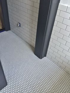 a bathroom with white tile and black doors