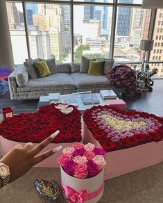 a heart shaped box with roses in it and a hand pointing at the flowers inside