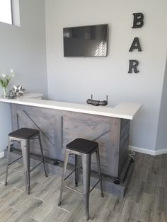 a bar with stools and a tv mounted on the wall above it in a room