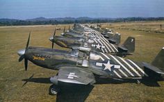 a row of fighter jets sitting on top of an open field