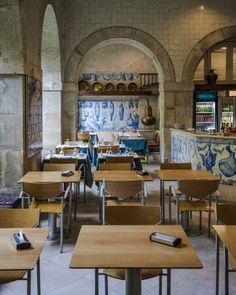 an empty restaurant with blue and white tiles on the walls, wooden tables and chairs