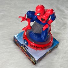 a spider man figurine sitting on top of a toy base next to a box