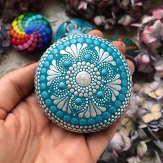 a hand holding a small blue and white beaded object in front of other beads