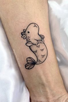 a black and white tattoo of a narwhale holding a fish