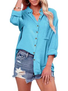 a woman wearing a blue shirt and denim shorts with her hand on her head, posing for the camera