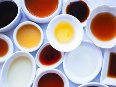 several bowls filled with different colored liquids on top of a white tablecloth,