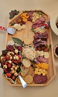 a wooden platter filled with cheese, crackers and meats