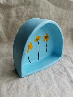 a blue vase with yellow flowers painted on it