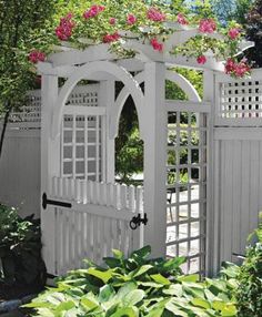 a white garden gate with pink flowers on it