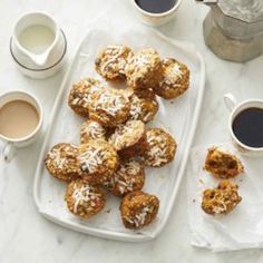 a tray filled with cookies next to two cups of coffee