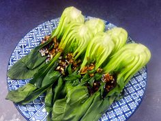 some green vegetables are on a blue and white plate