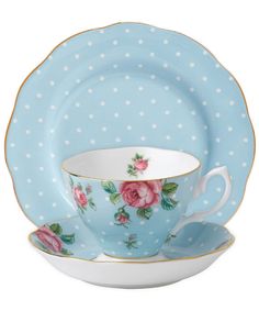 a polka dot tea cup and saucer set with pink roses on the side, sitting next to each other