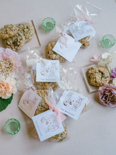 some cookies and flowers on a table with tags in the bags next to each other