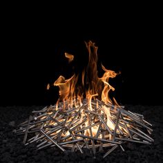 a pile of sticks sitting on top of a black ground covered in fire and flames