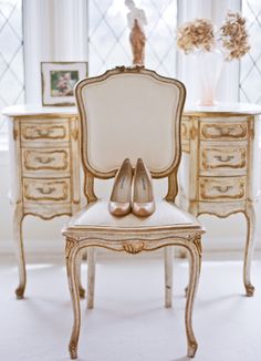 a pair of shoes sitting on top of a white chair in front of a window