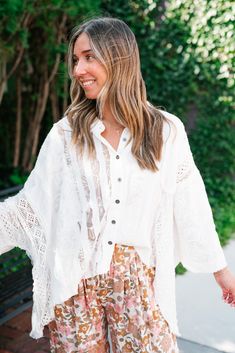 The Lakelyn Lace Ivory Button Up Top is a beautifully crafted, off-white lace and gauze blouse that exudes a romantic, bohemian vibe. The top features a delicate mix of lace and textured fabric, creating a soft and airy look perfect for layering. It has a button-down front with small, dark buttons that add a subtle contrast to the light fabric. The collar is slightly frayed, contributing to its relaxed and effortless style. The sleeves are voluminous and made entirely of intricate lace, adding a Loungewear Dresses, Short Leggings, Ivory Lace, Sandals For Sale, Skirt Leggings, White Lace, Long Tops, Short Tops, Effortless Style