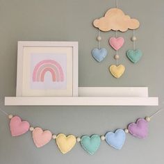 there are hearts hanging on the shelf with a rainbow in the background and a cloud above it