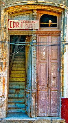 an old building with stairs leading up to the door and sign on the front window